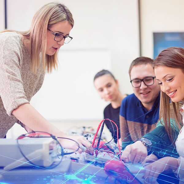 Eine Ausbilderin unterrichtet Auszubildende an elektrischen Messgeräten