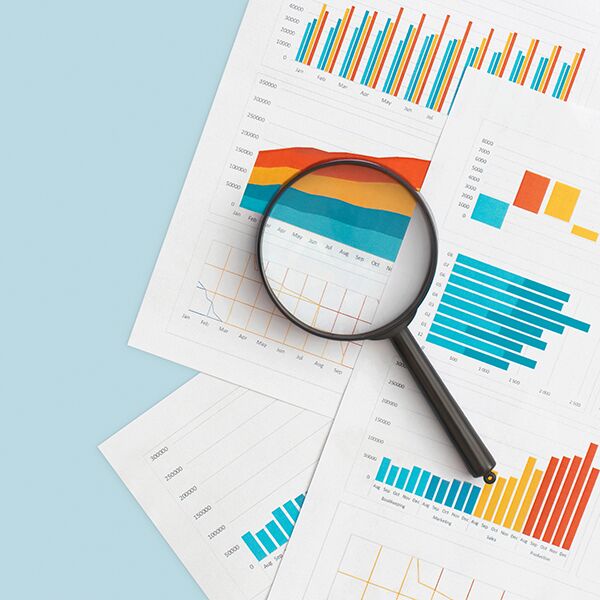 Eine Lupe liegt auf mehreren Bl&auml;ttern mit Diagrammen