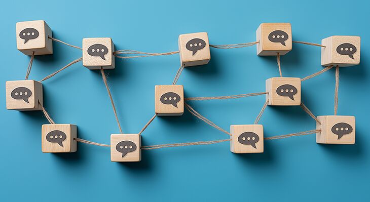 Holzw&uuml;rfel mit Sprechblasen, miteinander verbunden durch Schn&uuml;re