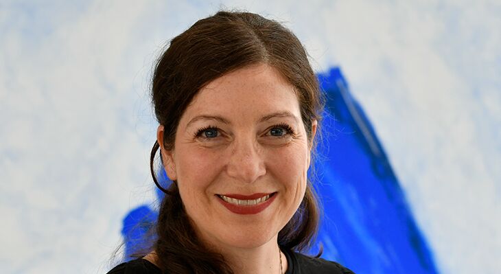 Myriam Schlupp-Winkler smiles at the camera, standing in front of a dark background in our BIBB building in Bonn.