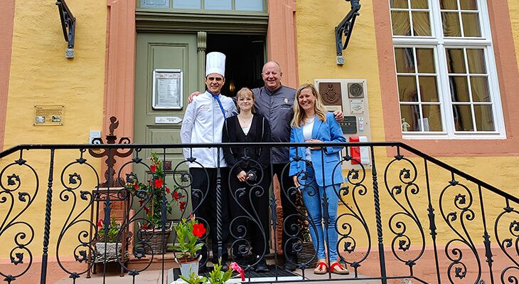Vier Personen stehen auf der Treppe eines Hotels und schauen in die Kamera