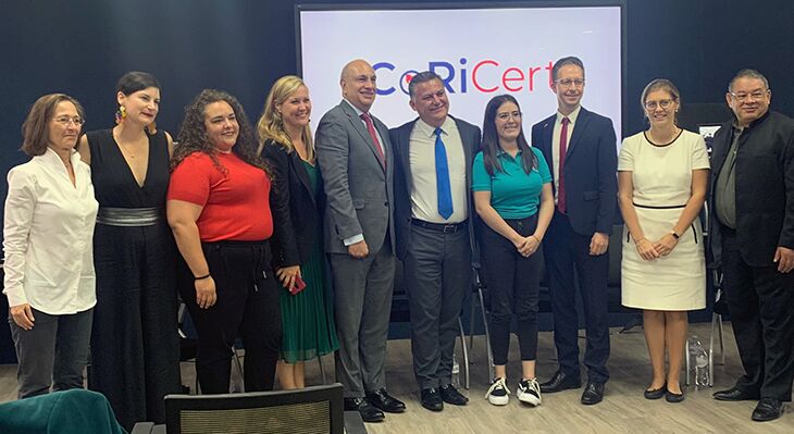 Die deutsche Delegation mit den costa-ricanischen Partnern auf einer Bühne in Costa Rica vor dem Logo des Projektes CoRiCert
