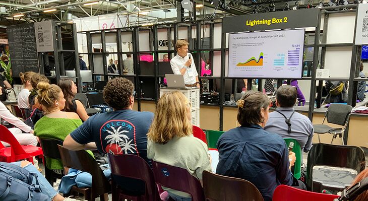 Speaker moderiert vor Bildschirmfolie zum Fachkräftemangel und Publikum auf der re:publica 2024